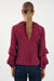 Model showing the back of marla blouse with straight hem and frilled collar and sleeves in burgundy by Adorne.