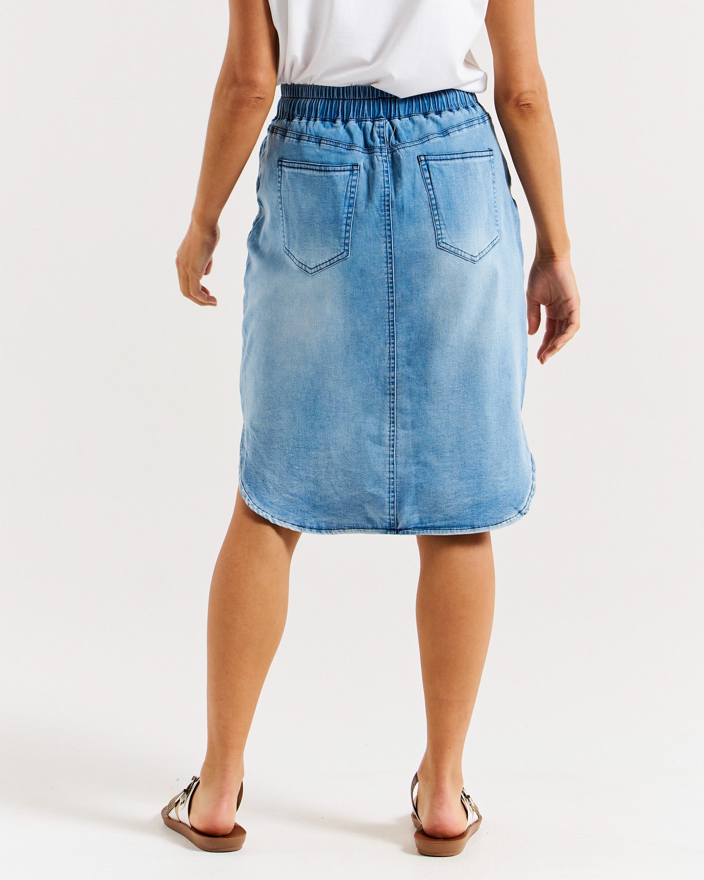 Model Showing Back of blue denim skirt with rounded hem and pull tie waist.