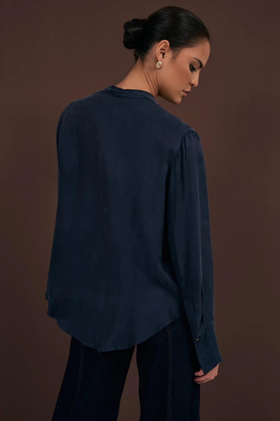 Back of Rylie Cupro Top showing curved hem and long sleeves with button detail.