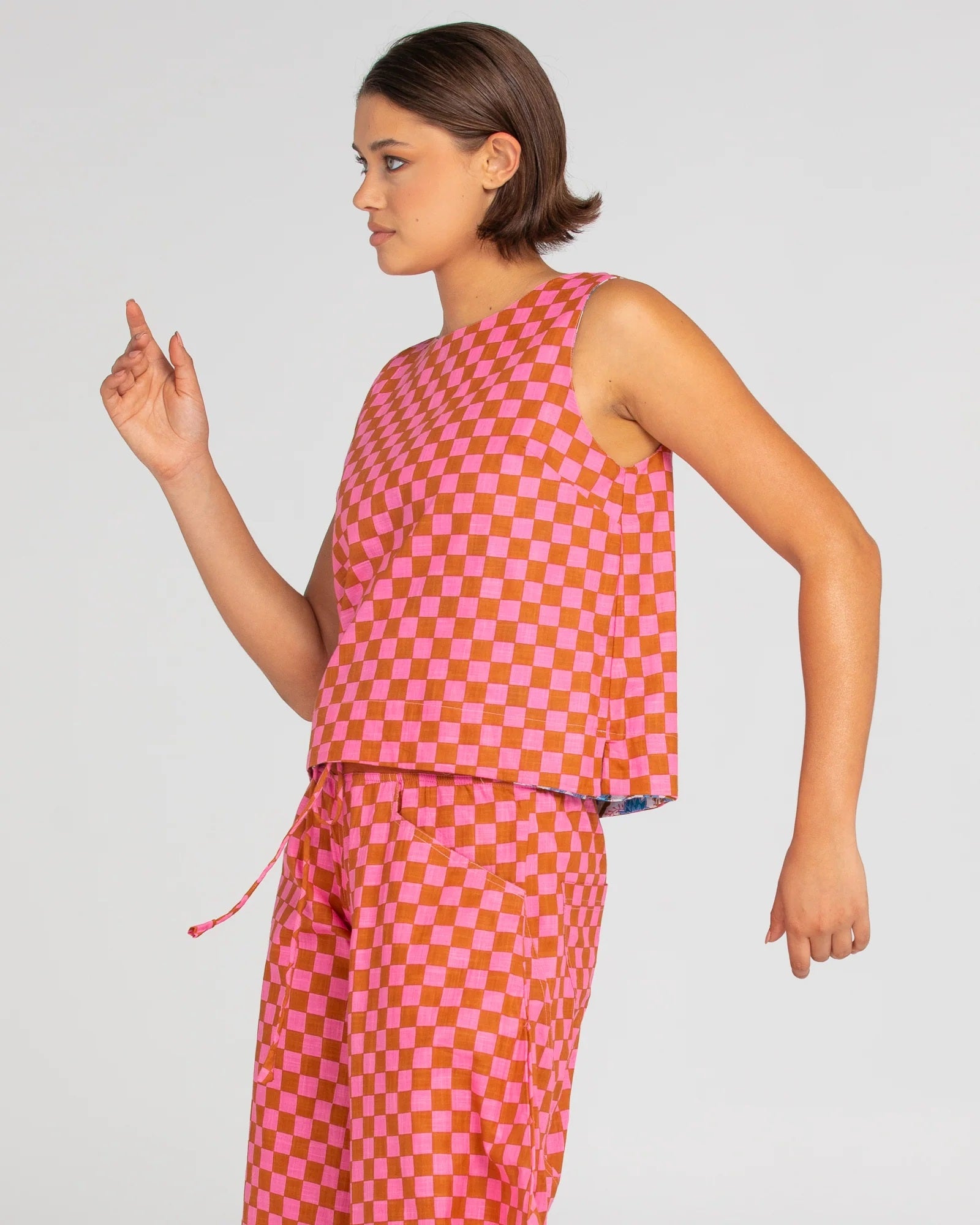 Side View of Hara Reversible Sleeveless Top in red and pink checks.